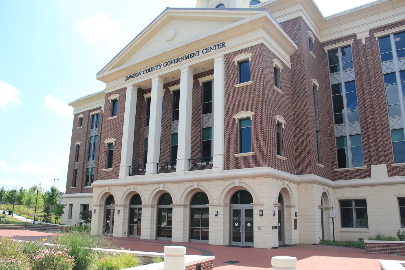 Brick and limestone Dawson County Government Center with a columned portico and arched ground-floor entrances