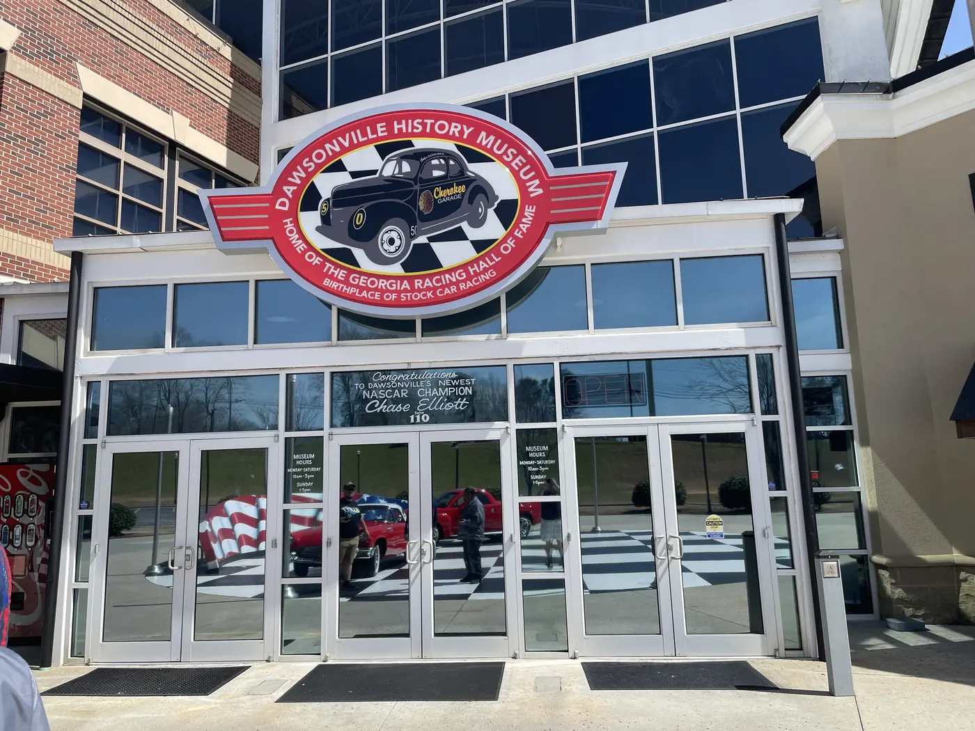 Glass entrance doors under a round Dawsonville History Museum sign showing a vintage race car and the words Home of the Georgia Racing Hall of Fame